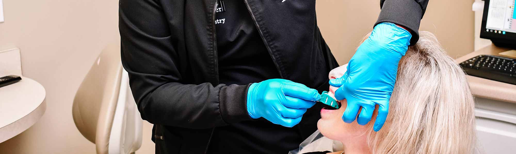 A dental assistant at Gildner Family Dentistry in Lexington, SC using a teal mold on a patients mouth to apply fluoride 