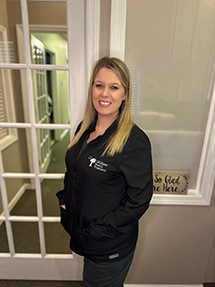 Allison Ard, registered dental hygienist, wearing a black smock in the doorway at Gildner Family Dentistry in Lexington, SC