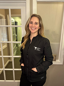 Kelly Rominger, Lead Expanded Duty Dental Assistant and Director of Marketing, wearing a black smock in the doorway at Gildner Family Dentistry in Lexington, SC