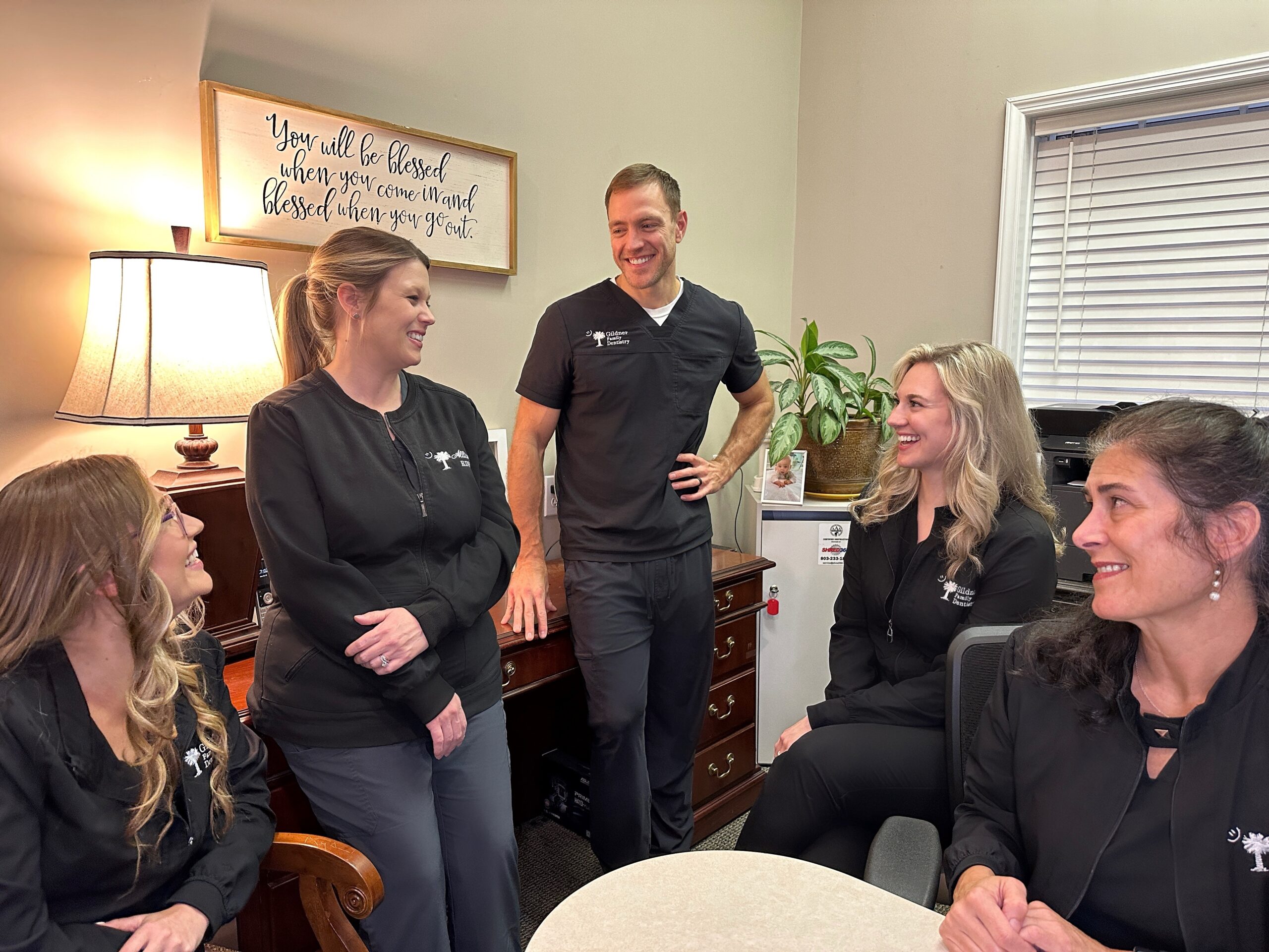 The dental team of Gildner Family Dentistry sitting together and laughing at Gildner Family Dentistry in Lexington, SC
