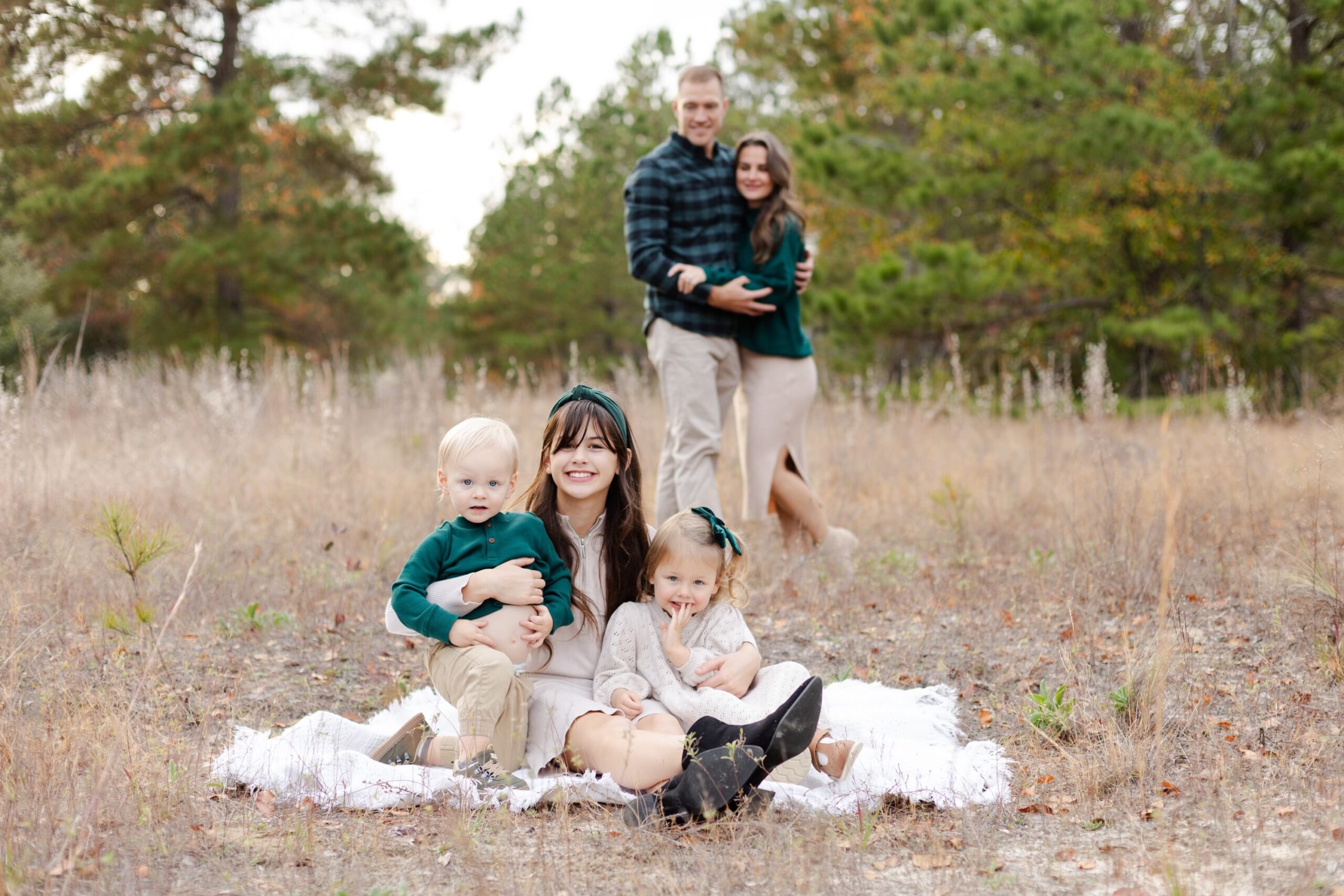 Dr. Robert Gildner's children smiling together for a photo in a serene woodland setting.