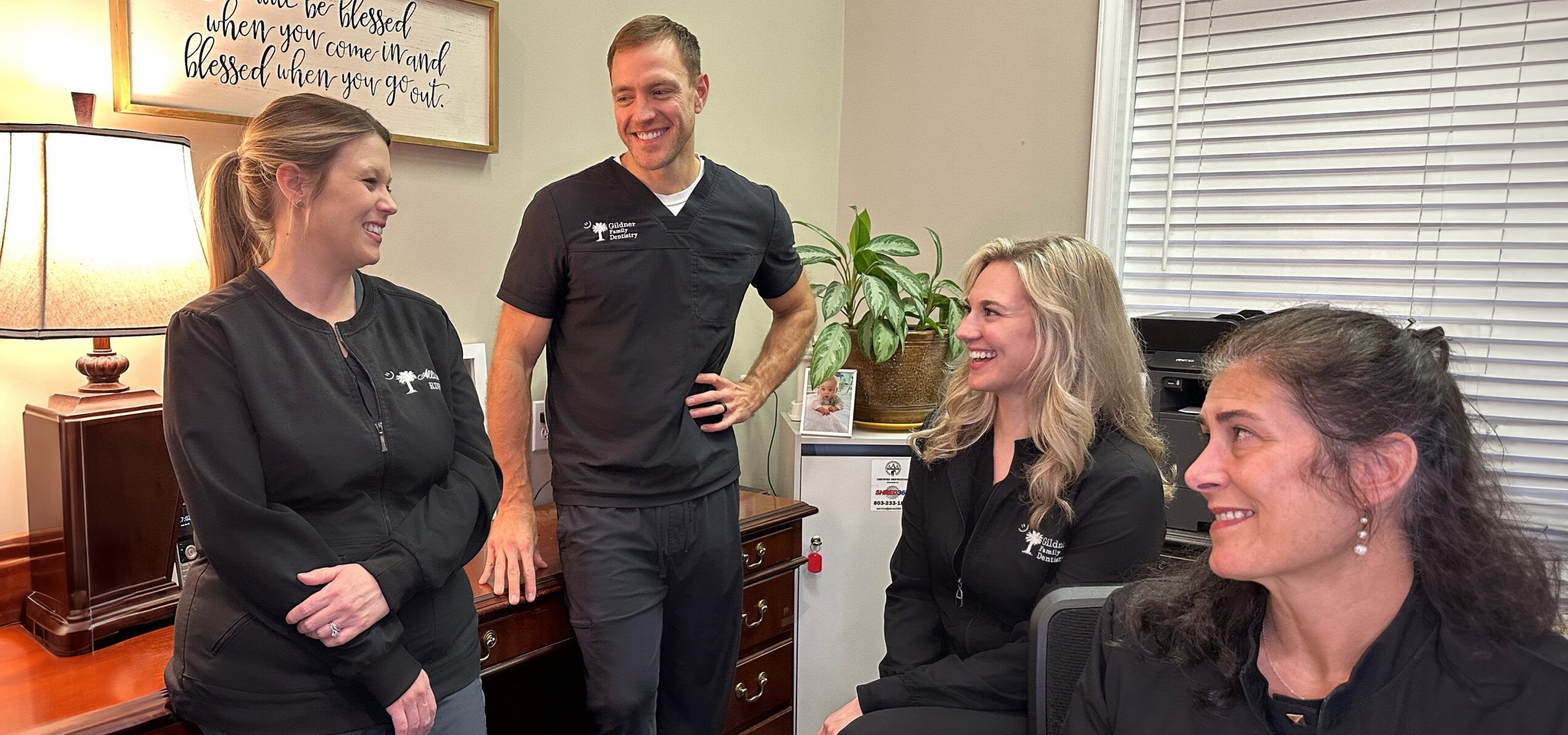 The dental team of Gildner Family Dentistry sitting together and laughing at Gildner Family Dentistry in Lexington, SC