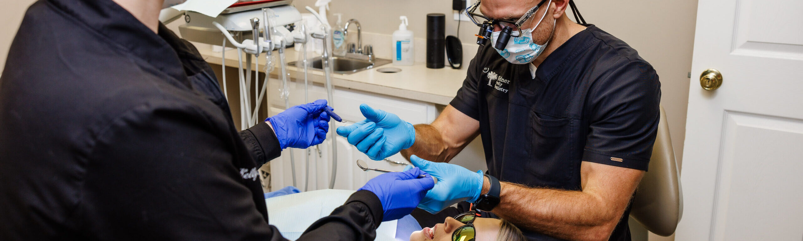 A dental assistant at Gildner Family Dentistry in Lexington, SC using a teal mold on a patients mouth to apply fluoride 