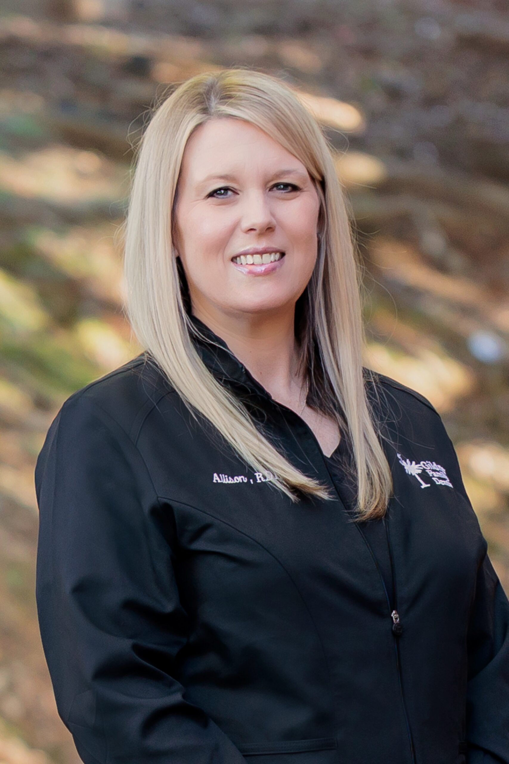 Allison Ard, registered dental hygienist, wearing a black smock in the doorway at Gildner Family Dentistry in Lexington, SC