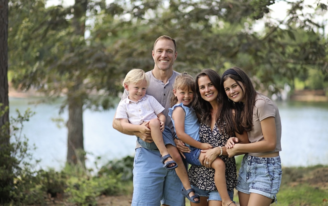 Dr. Robert Gildner's children smiling together for a photo in a serene woodland setting.