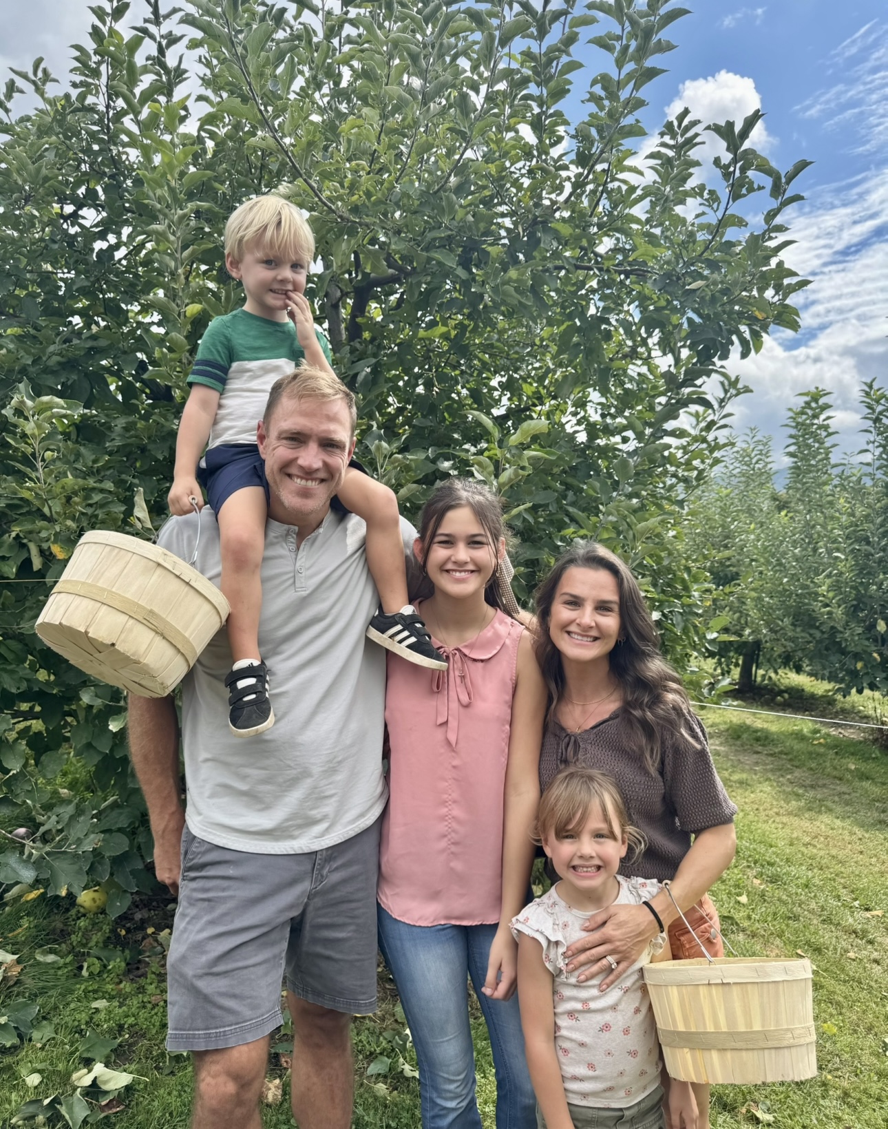 Dr. Robert Gildner's older daughter and two children sitting on a blanket in a field, enjoying a peaceful moment together.