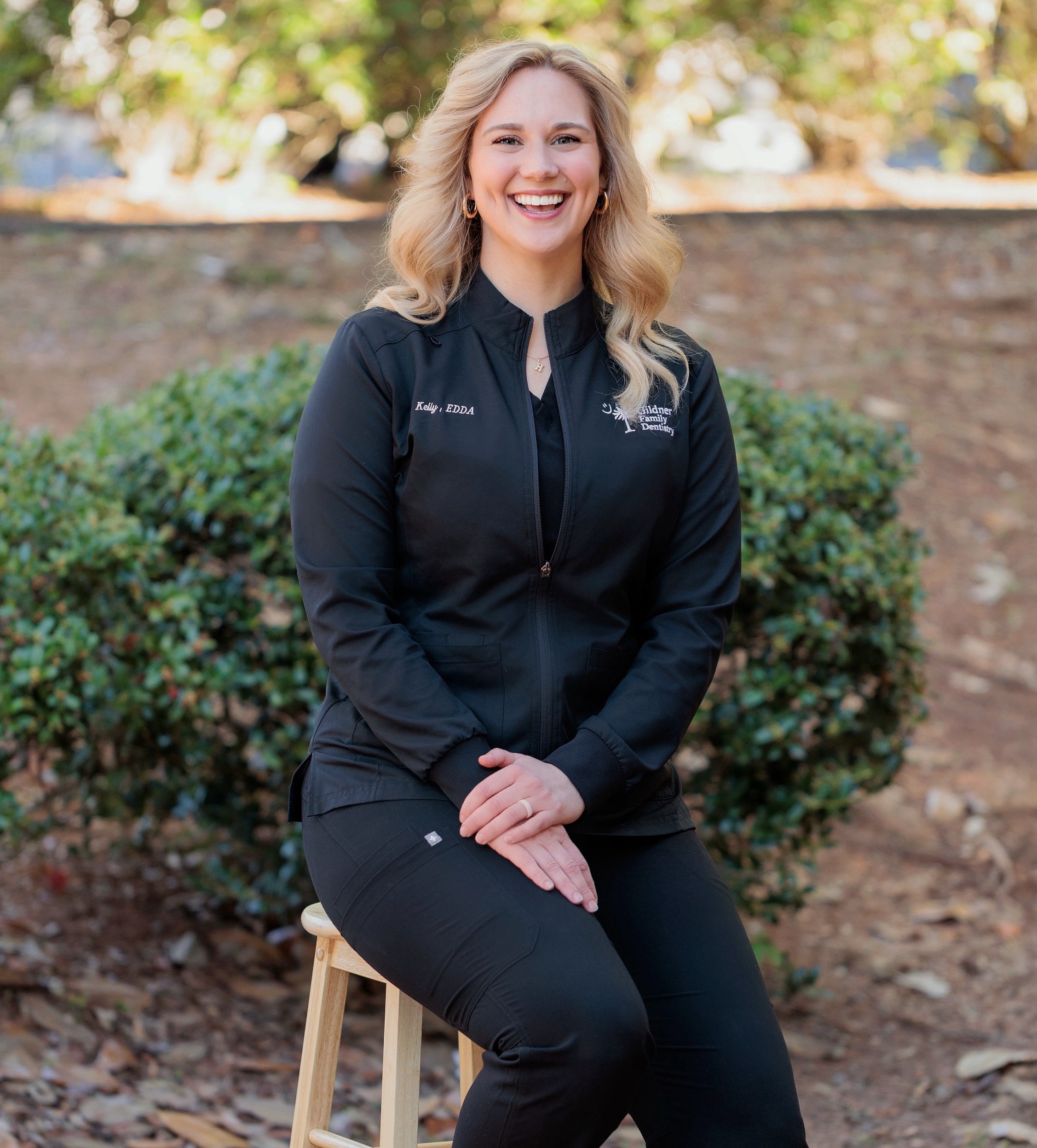 Kelly Rominger, Lead Expanded Duty Dental Assistant and Director of Marketing, wearing a black smock in the doorway at Gildner Family Dentistry in Lexington, SC